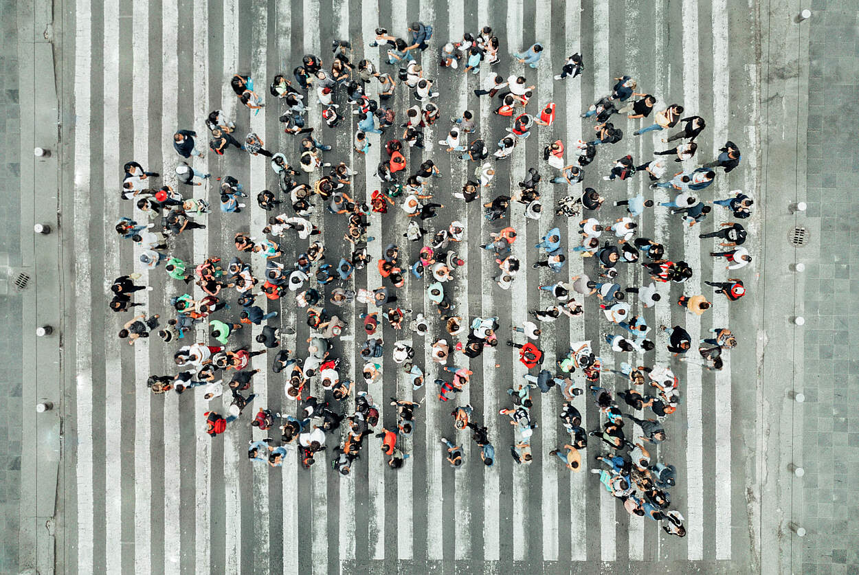 Menschengruppe auf einer Kreuzung in Form einer Sprechblase