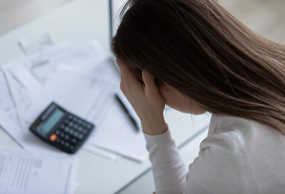 junge Frau verzweifelt Rechnungen Taschenrechner