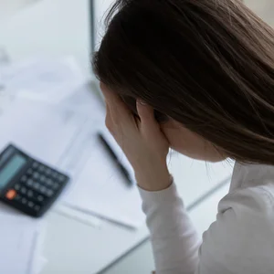 junge Frau verzweifelt Rechnungen Taschenrechner