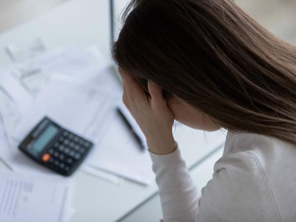 junge Frau verzweifelt Rechnungen Taschenrechner