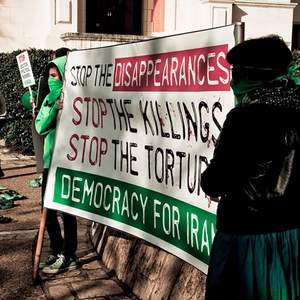 Frauen halten ein Banner gegen staatliche Folter und Mord im Iran
