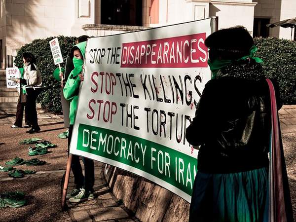 Frauen halten ein Banner gegen staatliche Folter und Mord im Iran