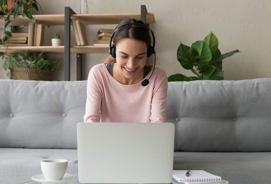 Junge Frau mit Headset vor Laptop