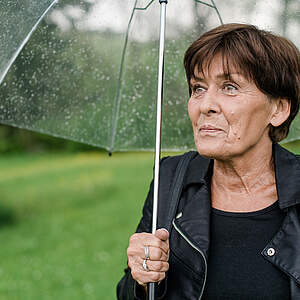 etwas ältere Frau mit Regenschirm
