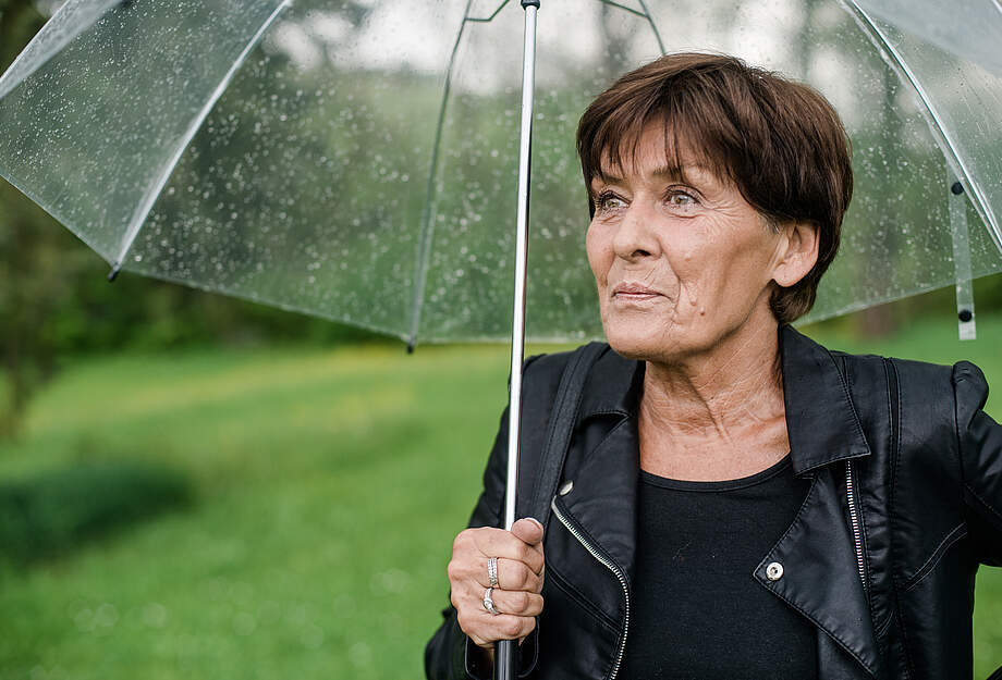 etwas ältere Frau mit Regenschirm