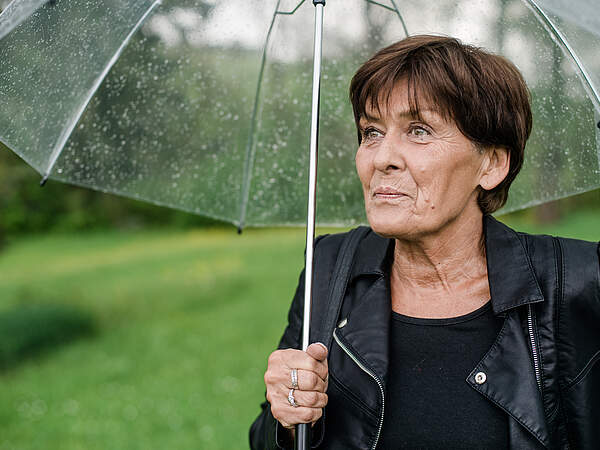 etwas ältere Frau mit Regenschirm