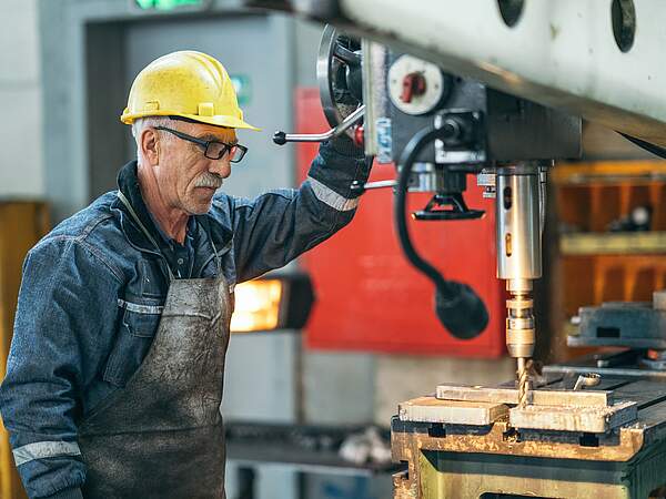 Älterer Arbeiter an einer Maschine in der Fabrik