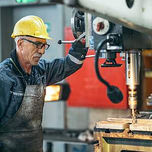 Älterer Arbeiter an einer Maschine in der Fabrik