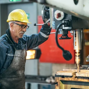 Älterer Arbeiter an einer Maschine in der Fabrik
