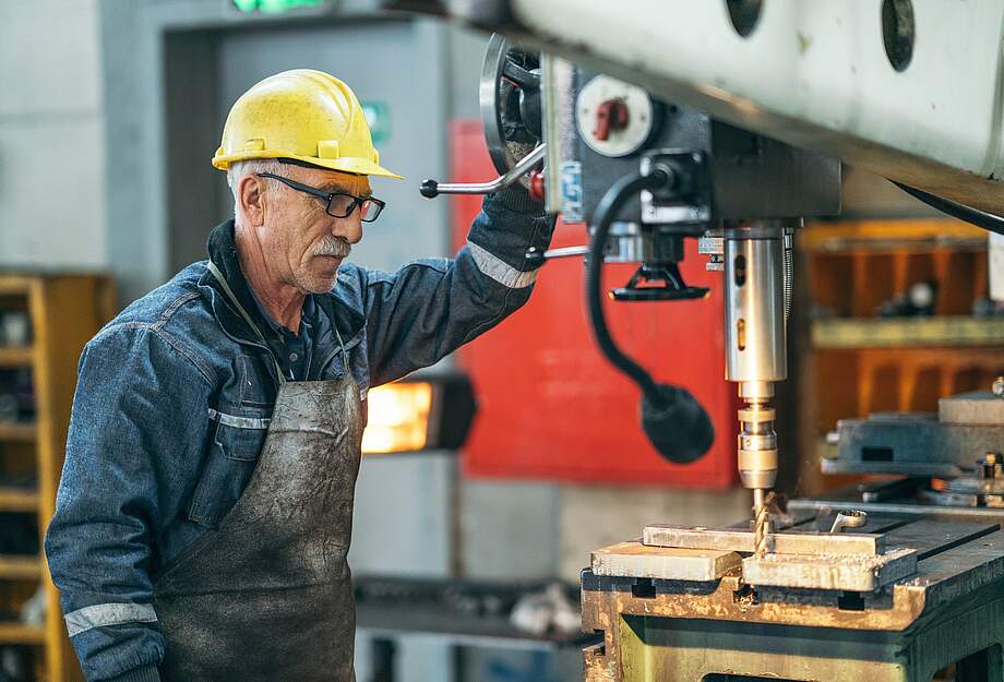 Älterer Arbeiter an einer Maschine in der Fabrik