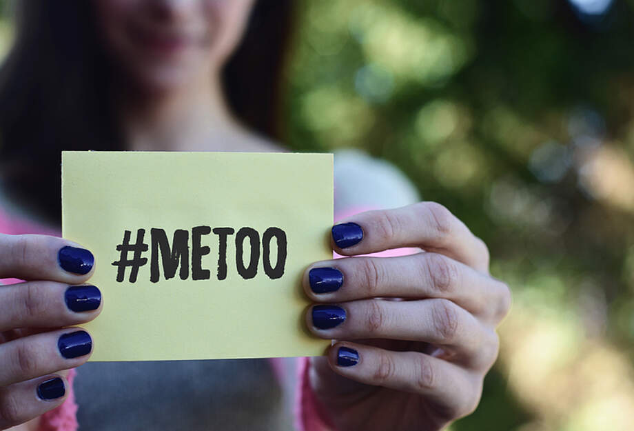 Frau hält einen Zettel mit #metoo in die Kamera