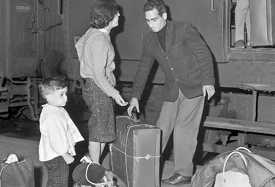 Sasonnier-Familie mit Koffern am Bahnhof