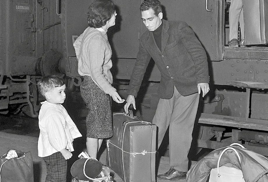 Sasonnier-Familie mit Koffern am Bahnhof
