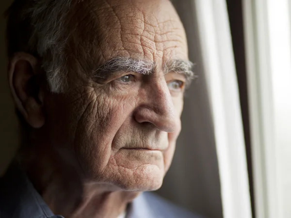 Nachdenklicher alter Mann Alter Mann schaut nachdenklich aus dem Fenster