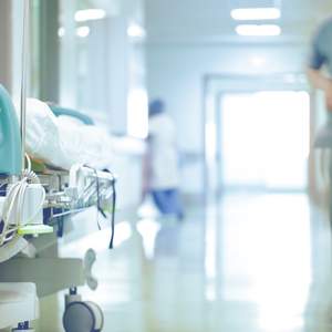 Blick in einen Spitalgang mit Bett und Pflegeperson